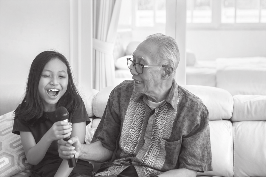 A girl and her grandfather sharing a microphone for a stimulus-based conversation prompt.